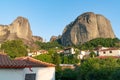 Houses and church in foothills among trees in valley below towering converging rocks and pinnacles at Meteora