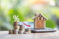 Houses and coins laying on a wooden table as a ladder with a white illustration showing a decrease in interest rates. plan savings