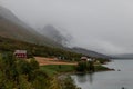 Houses at the feet of foggy mountains. Red farm house and fields. Royalty Free Stock Photo