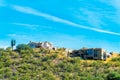 Houses on a hillside ridge in the sonora desert of Arizona with visble cactus and sprawling natural grasses and vegitation