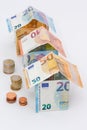 Houses made of 10, 20 and 50 euro banknotes, stacks of euro coins Royalty Free Stock Photo