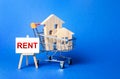 Houses in a shopping cart and an easel with a word Rent. Rental housing and apartments, choice between buying and renting Royalty Free Stock Photo