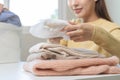 Housewife, asian young woman hand in many folding freshly shirts, sweaters or dress on desk, table after washing clean clothes and Royalty Free Stock Photo