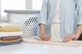 Housewife, asian young woman hand in many folding freshly shirts, sweaters or dress on desk, table after washing clean clothes and Royalty Free Stock Photo