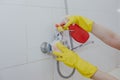 Housewife cleaning bathroom tap and shower Tap. Maid in yellow protective gloves washing dirty bath tap. Hands of woman washing Royalty Free Stock Photo