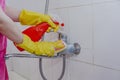 Housewife cleaning bathroom tap and shower Tap. Maid in yellow protective gloves washing dirty bath tap. Hands of woman washing Royalty Free Stock Photo