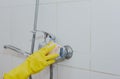 Housewife cleaning bathroom tap and shower Tap. Maid in yellow protective gloves washing dirty bath tap. Hands of woman washing Royalty Free Stock Photo