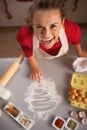 Housewife drawing christmas tree on kitchen table with flour