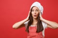 Housewife female chef cook or baker in red striped apron, white t-shirt, toque chefs hat isolated on red wall background Royalty Free Stock Photo