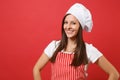 Housewife female chef cook or baker in red striped apron, white t-shirt, toque chefs hat isolated on red wall background Royalty Free Stock Photo