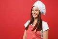 Housewife female chef cook or baker in red striped apron, white t-shirt, toque chefs hat isolated on red wall background Royalty Free Stock Photo