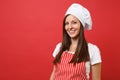 Housewife female chef cook or baker in red striped apron, white t-shirt, toque chefs hat isolated on red wall background Royalty Free Stock Photo