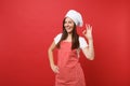 Housewife female chef cook or baker in striped apron, white t-shirt, toque chefs hat isolated on red wall background Royalty Free Stock Photo