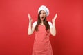 Housewife female chef cook or baker in striped apron, white t-shirt, toque chefs hat isolated on red wall background Royalty Free Stock Photo