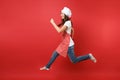 Housewife female chef cook or baker in striped apron white t-shirt, toque chefs hat isolated on red wall background