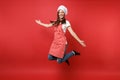 Housewife female chef cook or baker in striped apron white t-shirt, toque chefs hat isolated on red wall background