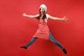 Housewife female chef cook or baker in striped apron white t-shirt, toque chefs hat isolated on red wall background