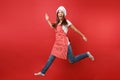 Housewife female chef cook or baker in striped apron white t-shirt, toque chefs hat isolated on red wall background