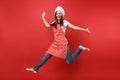 Housewife female chef cook or baker in striped apron white t-shirt, toque chefs hat isolated on red wall background