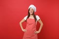 Housewife female chef cook or baker in striped apron, white t-shirt, toque chefs hat isolated on red wall background Royalty Free Stock Photo