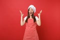 Housewife female chef cook baker in striped apron, white t-shirt, toque chefs hat isolated on red wall background Royalty Free Stock Photo