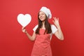 Housewife female chef cook or baker in striped apron, white t-shirt, toque chefs hat isolated on red wall background Royalty Free Stock Photo