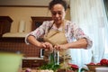 Housewife filling jar with spicy chili peppers, chopped fresh dill leaves, garlic when pickling seasonal vegetables