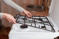 Housewife hold metal grates to clean the dirty kitchen gas stove.