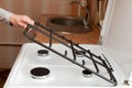 Housewife hold metal grates to clean the dirty kitchen gas stove. Royalty Free Stock Photo