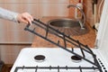 Housewife hold metal grates to clean the dirty kitchen gas stove.