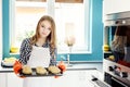 Housewife holding hot roasting pan with freshly baked bread rolls.