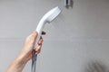 Housewife holds in her hand cleen and closed off rain shower head in the bathroom