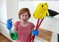 Housewife at home kitchen in gloves holding cleaning broom and mop and spray bottle