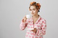 Housewife making procedures on weekend. Portrait of cute and funny european woman in hair curlers and nightwear with Royalty Free Stock Photo