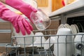 Housewife putting dirty dishware in dishwasher rack at home kitchen