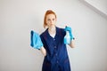 Housewife with red-haired ponytail holds dusting cloth and wiper. Royalty Free Stock Photo