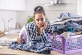 Housewife reluctantly looks at the pile of clothes that need ironing with an iron in her hand Royalty Free Stock Photo
