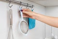 housewife removes kitchen strainer from hook on rail.