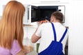 Housewife and repairman near microwave oven Royalty Free Stock Photo