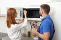 Housewife and repairman near microwave oven Royalty Free Stock Photo