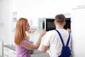 Housewife and repairman near microwave oven Royalty Free Stock Photo