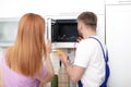 Housewife and repairman near microwave oven Royalty Free Stock Photo