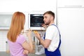 Housewife and repairman near microwave oven Royalty Free Stock Photo