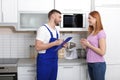 Housewife and repairman near microwave oven Royalty Free Stock Photo