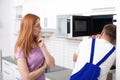 Housewife and repairman near microwave oven Royalty Free Stock Photo