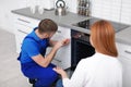Housewife with repairman near modern oven Royalty Free Stock Photo