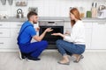 Housewife with repairman near modern oven Royalty Free Stock Photo