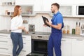 Housewife with repairman near modern oven Royalty Free Stock Photo