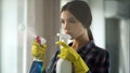 Housewife spraying different window cleaners on glass, bringing house to order