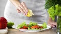 Housewife sprinkling vegetable salad with lemon juice, rich in vitamins food